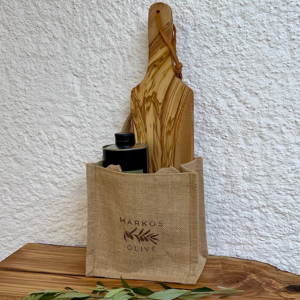 Jute-Geschenktasche von MARKOS OLIVE mit 1 L Agianna Premium Olivenöl, Kalamata-Oliven und handgefertigtem Olivenholzbrett mit Stielgriff.