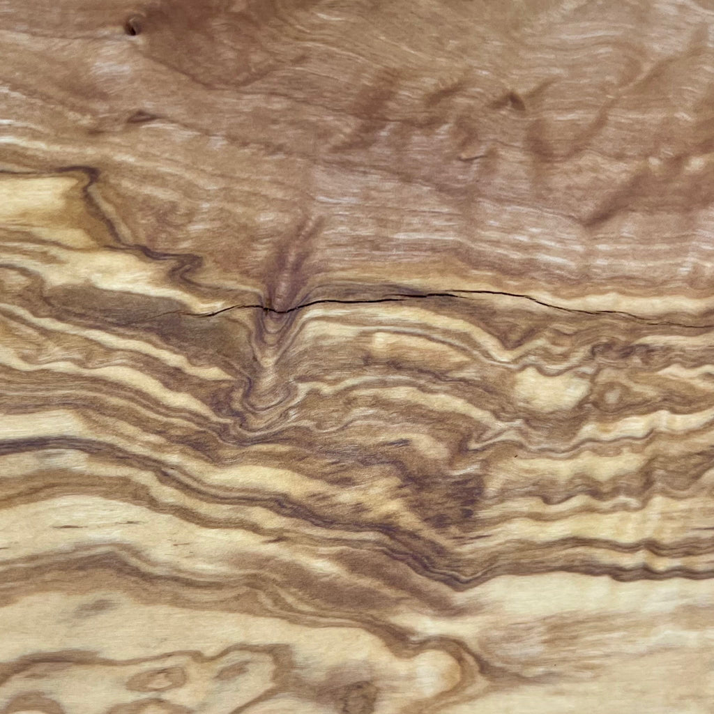 Nahaufnahme der lebendigen Maserung eines 45 cm Olivenholzbretts in Naturform