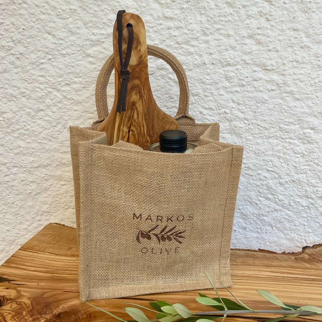 Hochwertiges Geschenkset „Kochfreude“ von MARKOS OLIVE mit Olivenöl, Glas Kalamata-Oliven und Olivenholzbrett in dekorativer Jutetasche.