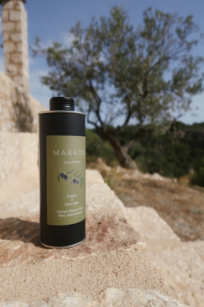 Eine Flasche MARKOS OLIVE AGIANNA Olivenöl steht auf eine Steintreppe in Griechenland