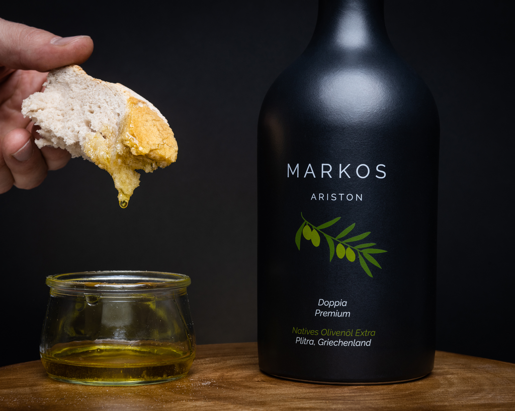 MARKOS OLIVE PREMIUM OLIVENOEL wird mit einem Stück Brot verkostet. Das Brot wurde in einem Glas mit Olivenoel eingetaucht