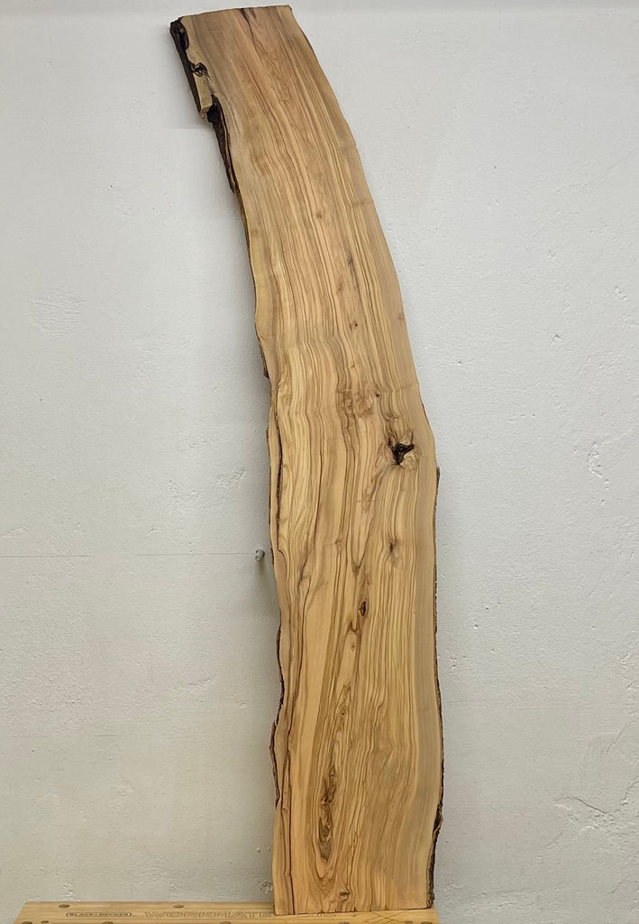Rechte Seitenansicht eines langen Olivenholz-Bretts mit naturbelassener Rinde und weich fließender Maserung – ideal für Möbelbau oder Tischplatten.
