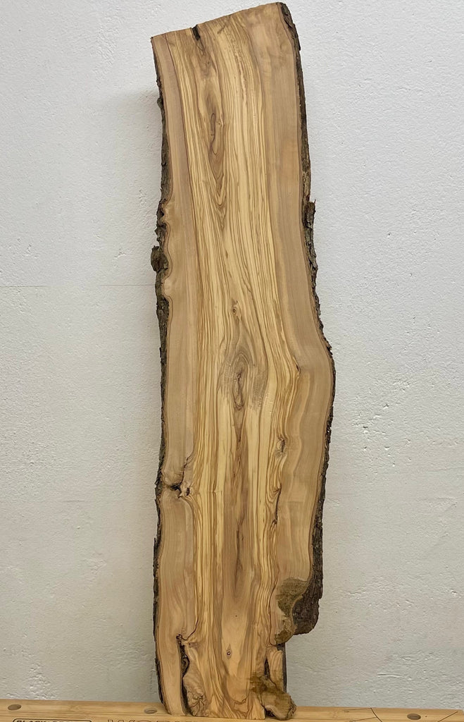 Gesamtansicht der massiven Olivenholzbohle mit natürlicher Rindenkante, typischer Fladerung und organisch gewachsener Form – 95 cm Länge, ideal für Möbelprojekte.