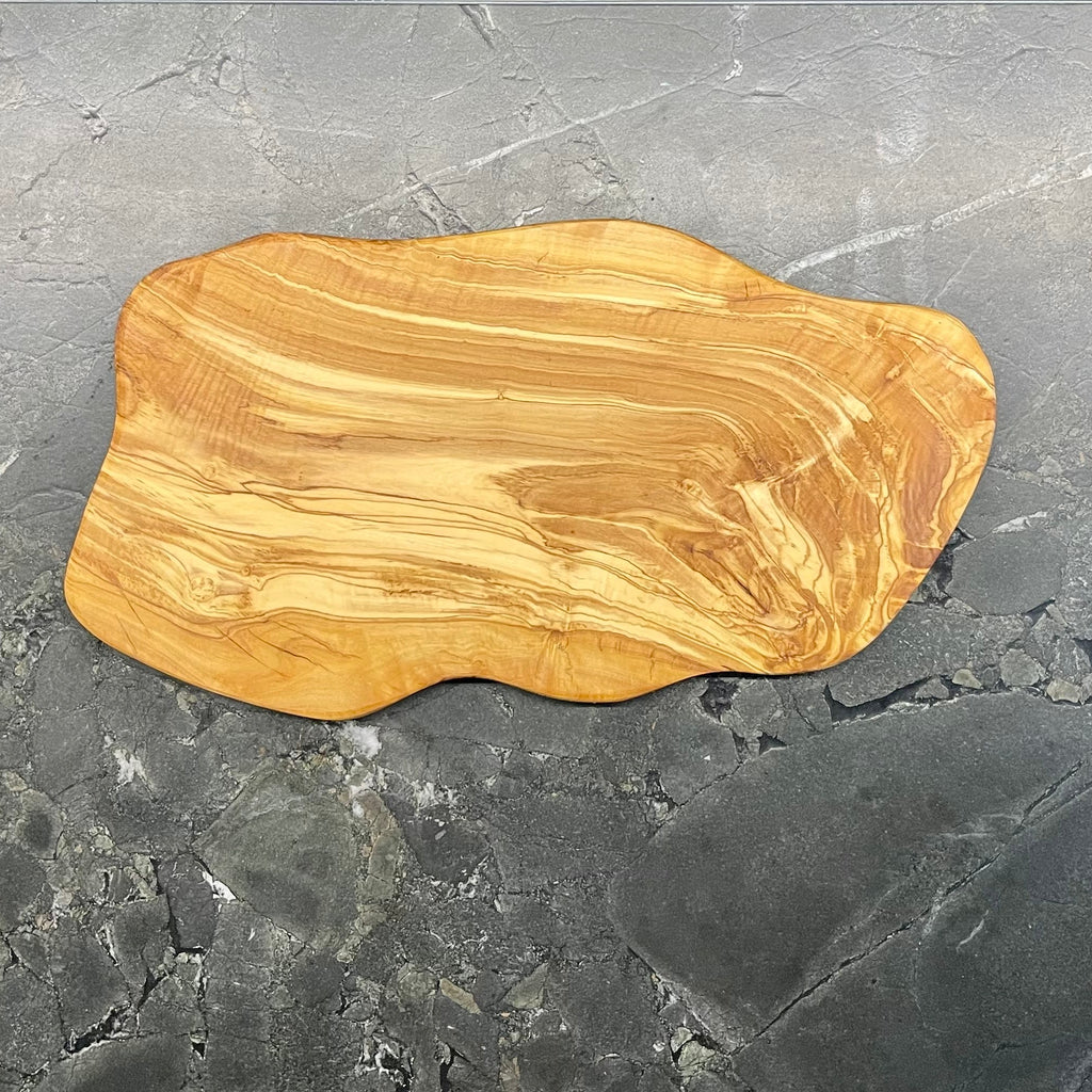 Rückseite eines massiven Olivenholzbretts in organischer Form mit charaktervoller, goldbrauner Maserung