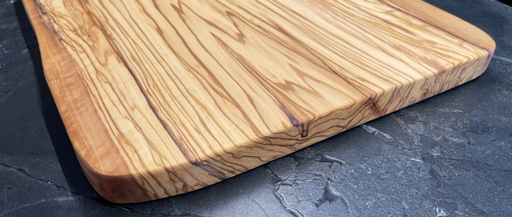 Hochwertiges Schneidebrett aus massivem Olivenholz von MARKOS OLIVE mit lebendiger, natürlicher Maserung – robust, langlebig und ideal zum Schneiden und Servieren.