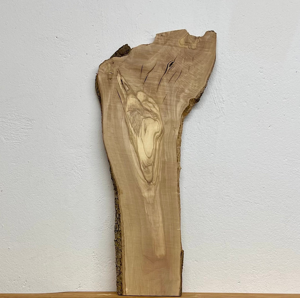 Olivenholz-Brett W506 mit Naturkante, markanter Maserung und Rissen, 640 × 270–160 × 16 mm.