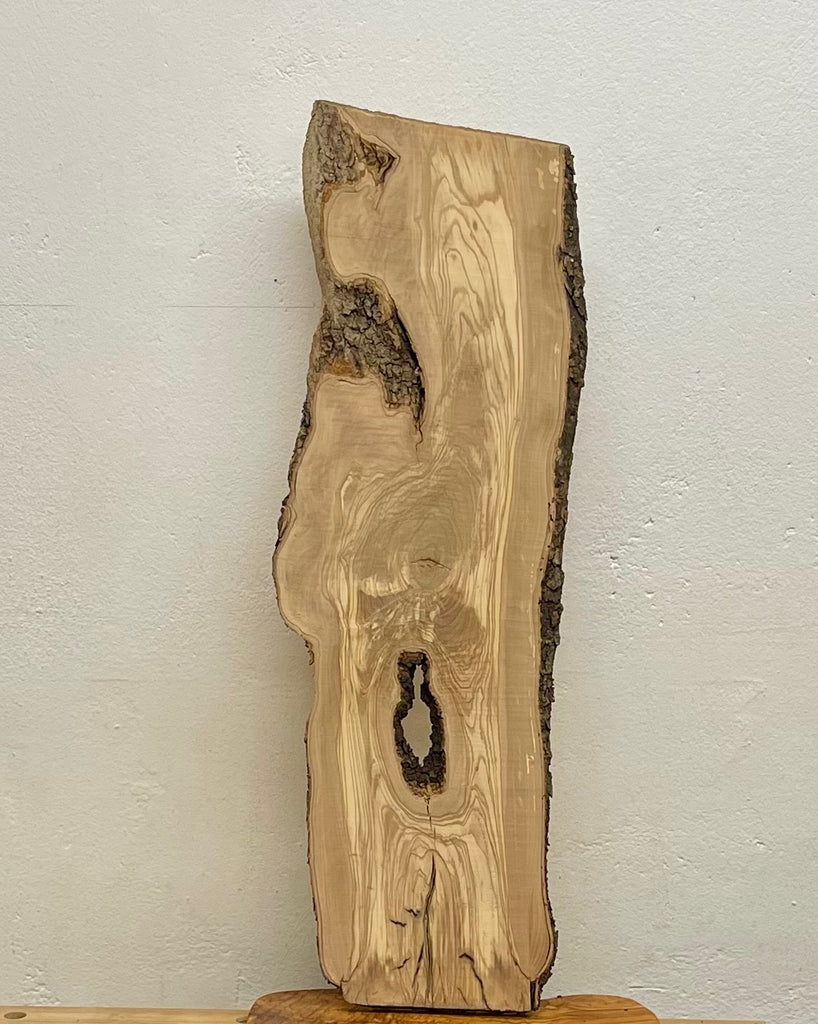 Olivenholz-Designbrett W509 mit Naturkante und großem Astloch, 760 × 250–200 × 15 mm.